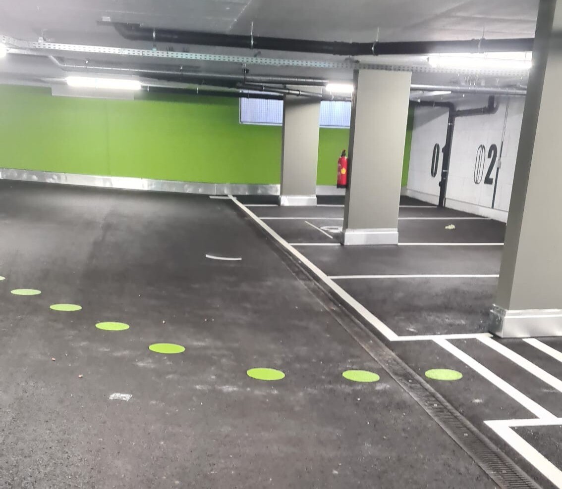 Tiefgarage mit grünen Farbakzenten und weißen Markierungen